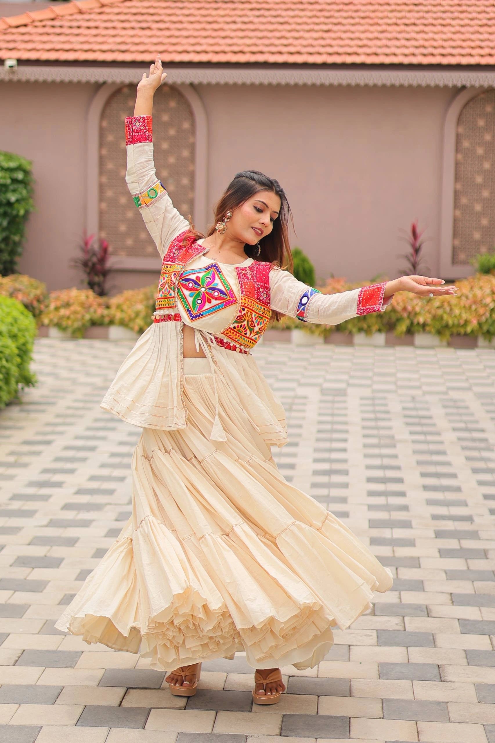 Woman in traditional outfit dancing outdoors on a paved area.